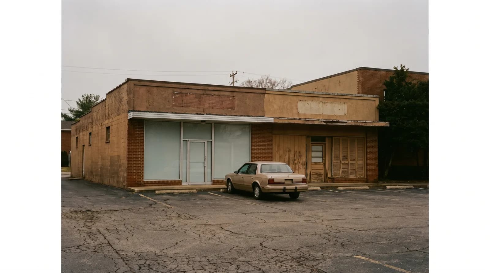 A small two-tenant strip center seen across an empty parking lot under overcast light.